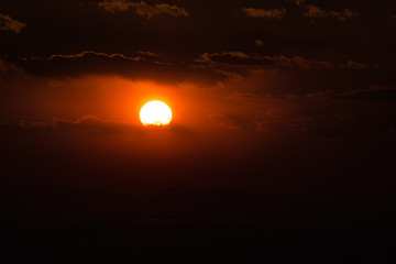 Dramatic sunset sky with orange colored clouds and sun.