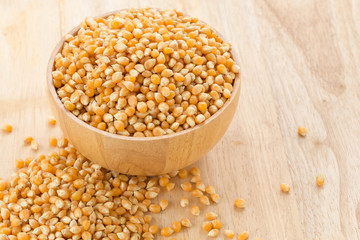 Wooden bowl with corn seeds on wooden table