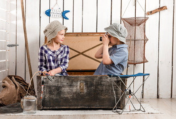 little boy shooting little girl sitting in old big chest