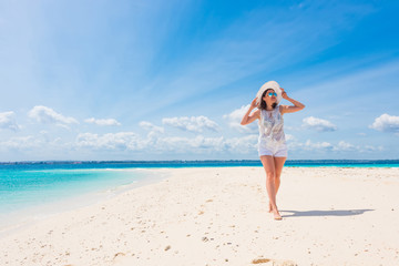 Obraz premium beautiful smiling girl in hat on a beach of blue ocean and sky on the background