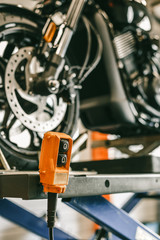 Fototapeta premium Closeup up down hydraulic controller switch on a lift with a motorcycle. Bike during maintenance, repair.