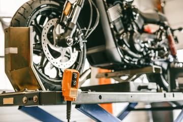 Closeup up down hydraulic controller switch on a lift with a motorcycle. Bike during maintenance, repair.