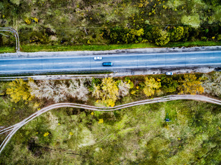 top view of car on asphalt track with colorful trees and rolled road on one side, aerial photo