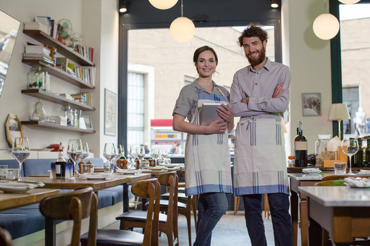 Two proud restaurateurs smiling at camera