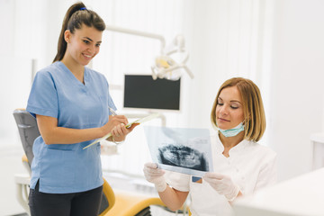 woman dentist with her assistant examine dental x-ray