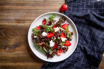 Strawberry salad with balsamic vinegar, fennel, cream cheese, walnuts and greens. Easy summer food concept. Wooden background, copy space.