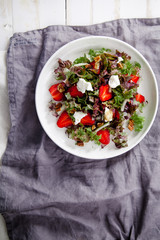 Plate of strawberry salad with balsamic vinegar, fennel, cream cheese, walnuts and greens on gray linen napkin. Easy summer food concept.
