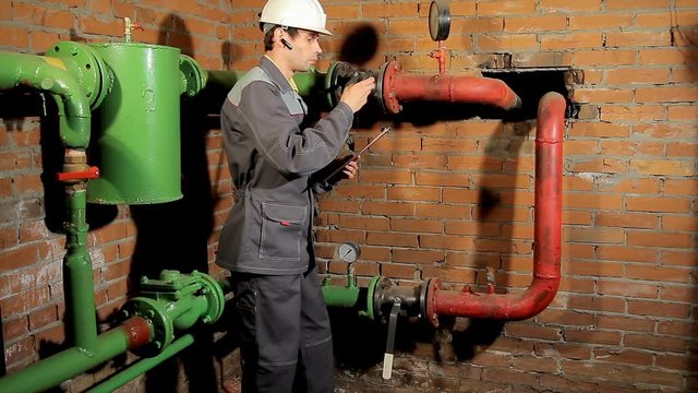 The worker measures the temperature of the heating pipe with a laser pyrometer. Verifies the results obtained. take meter readings.