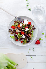 Strawberry salad with balsamic vinegar, fennel, cream cheese, walnuts and greens. Easy summer food concept. White fabric background