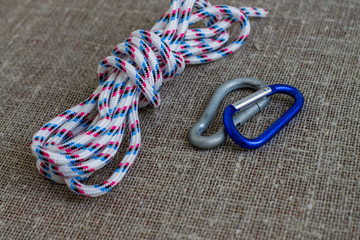 Striped nylon rope and two carabine on a background of sackcloth. Close up