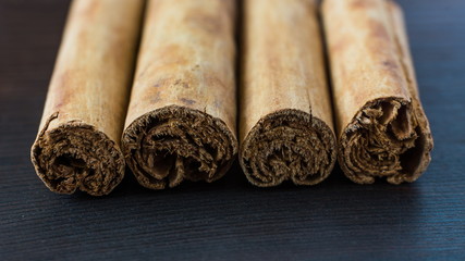 Ceylon cinnamon sticks on black wooden surface close-up
