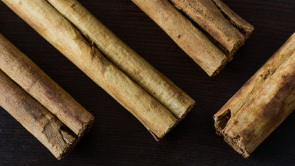 Ceylon cinnamon sticks on black wooden surface close-up