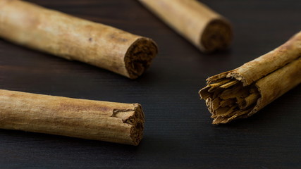 Ceylon cinnamon sticks on black wooden surface close-up