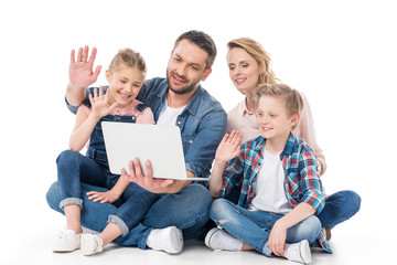 happy family using laptop while sitting on floor isolated on white