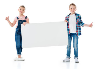Adorable boy and girl holding blank banner and showing thumbs up sign