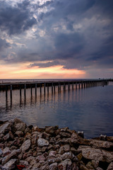 Evening sky,rows of bamboo sticks in the sea and cement bridge near Matchanu Shrine,Phanthai Norasing,Mueang Samut Sakhon District,Samut Sakhon,Thailand.