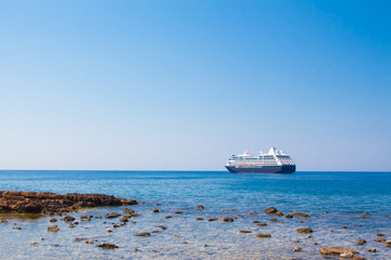 View of the sea coast with stones and boat in Chania, Crete island, Greece.