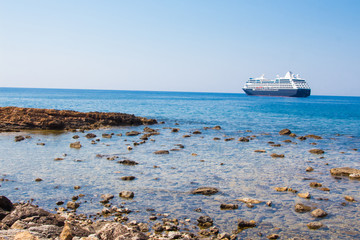 View of the sea coast with stones and boat in Chania, Crete island, Greece.