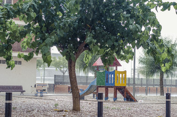 It is raining in a children's playground, rain drops falling