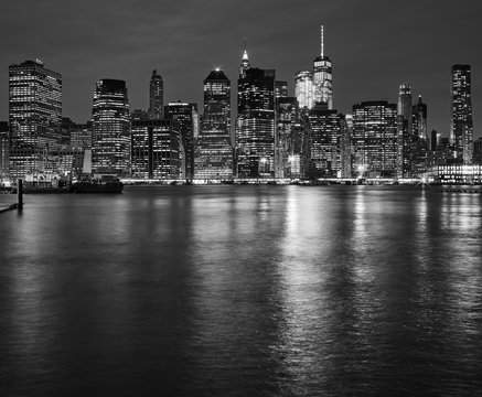 Fototapeta Manhattan skyline reflected in East River at night, New York City, USA.