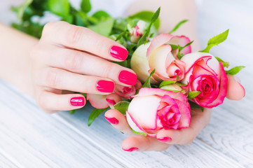 Fototapeta na wymiar Hands with pink manicured fingernails and beautiful roses