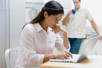 Woman using a laptop computer in kitchen