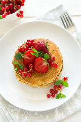 Tradition breakfast: stack of pancakes with berries decorated mint leaves on white wooden table. Selective focus