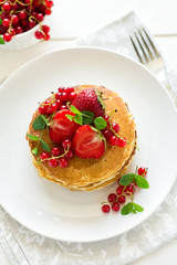 Tradition breakfast: stack of pancakes with berries decorated mint leaves on white wooden table. Selective focus