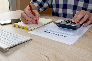 A businessman doing some paperwork using his calculator. Businessman hand holding ballpoint pen working on computer, working online concept