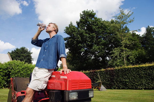 Man Drinking Water By Lawn Mover