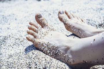 Holiday concept. Woman feet close-up relaxing on beach, enjoying sun and splendid view