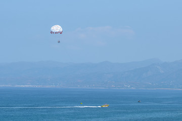 Parachuting over a sea, towing by a boat. Riding on a parachute behind a boat. Travel concep