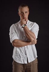 Stylish blond male model in casual clothes posing in studio on black background. 