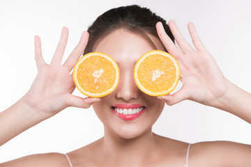 Beautiful young asian woman with orange slices cover her eyes.