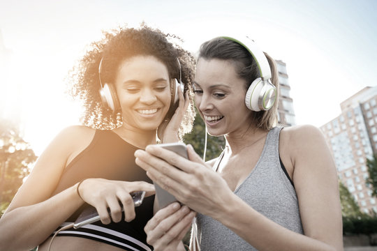 Girlfriends listening to music with smartphone while exercising