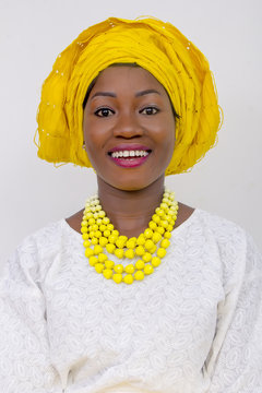 an African lady with head tie, bead necklace, beautiful makeup and smiling