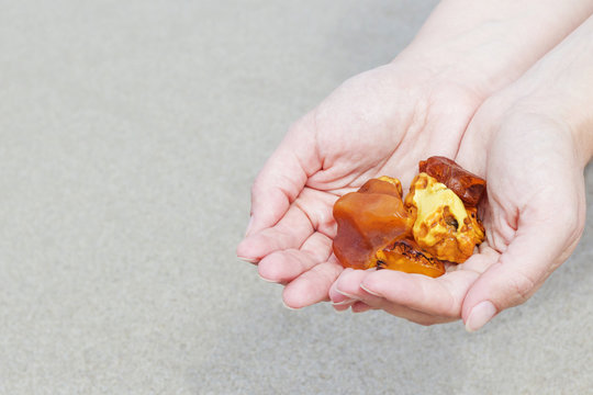 Amber in the hand with a bright reflection on the palm against the background of the sea.