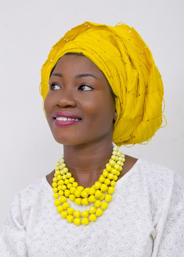 an African lady with head tie, bead necklace, beautiful makeup and smiling