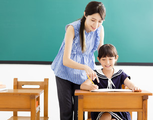 young Teacher helping child with writing lesson.