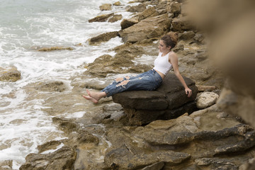 Teenage girl sitting on the rocks.