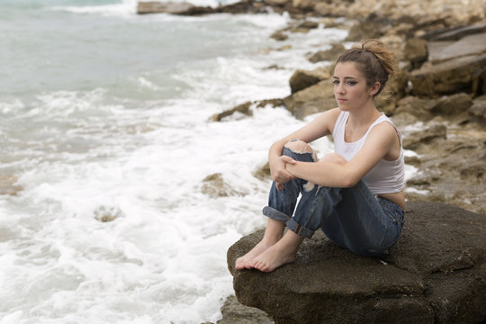 Teenage girl sitting on the rocks.