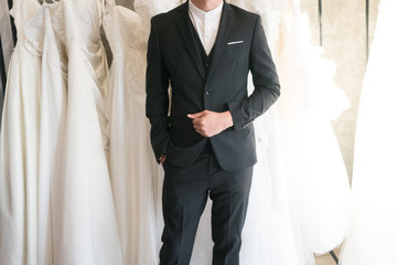 groom try wearing  suit in front of the bride dress