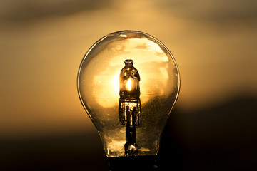 The bulb on blurry yellow background during sunset. Detail of glass bulb.