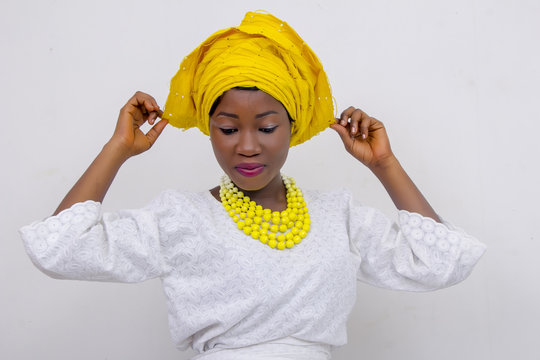 an African lady with head tie, bead necklace, beautiful makeup and smiling