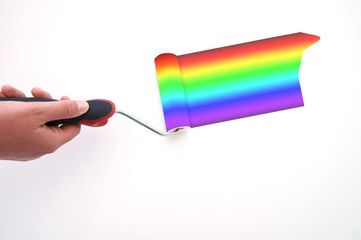 A woman hand painting a white wall with a roller using rainbow colors
