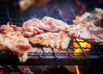 Close up barbecue pork roasting on charcoal grill with bright flame Selective focus.