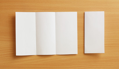 Blank Trifold white template paper on wood background with soft shadows. Ready for your design