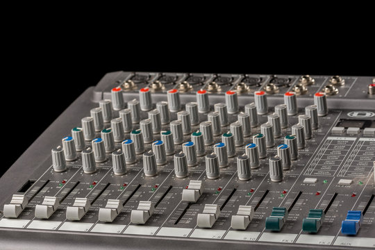 Audio mixing console with knobs and sliders and black background