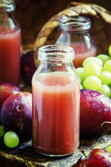 Fototapeta na wymiar Plum and grape fruit juice in glass bottles, selective focus