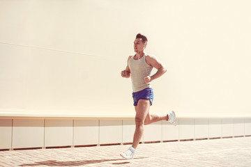 Fitness, workout, sport, lifestyle concept - sportsman running in sunny evening city